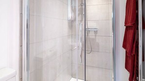 A glass-enclosed shower with a handheld showerhead and a wall-mounted faucet. - Host & Stay | Wilson Studio (Brighton and Hove)
