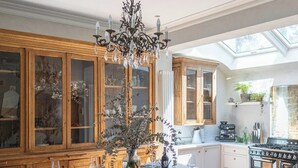 A modern kitchen with wooden cabinets, a central island with chairs, a chandelier, and a skylight. - Host & Stay | The Walpole House (Brighton and Hove)