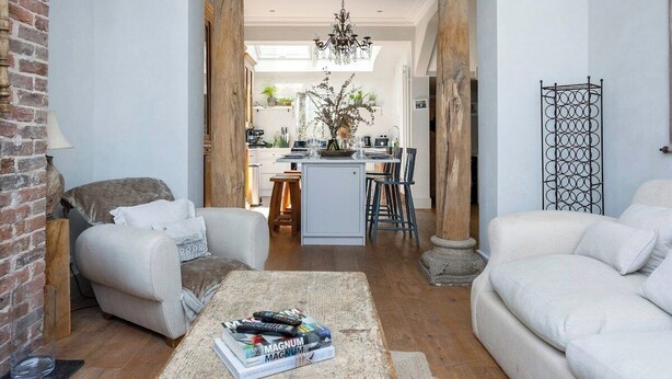 A living room with a fireplace, a coffee table with books, and a view into the kitchen. - Host & Stay | The Walpole House (Brighton and Hove)