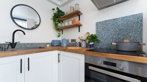 A modern kitchen with white cabinets, a black faucet, a granite backsplash, and a built-in oven. - Host & Stay | Islingword Studio (Brighton and Hove)
