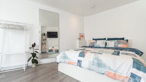 A modern bedroom with a large bed, a walk-in closet, and a mirror. - Host & Stay | Islingword Studio (Brighton and Hove)