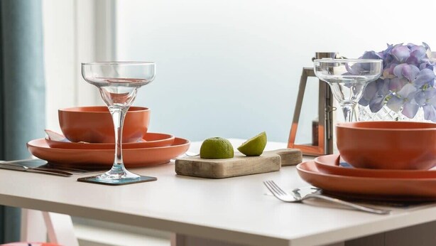 A dining table with orange plates, a clear glass, and lime halves. - Host & Stay | Islingword Studio (Brighton and Hove)