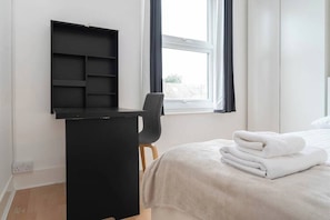Une chambre à coucher avec un lit, un bureau et une fenêtre.