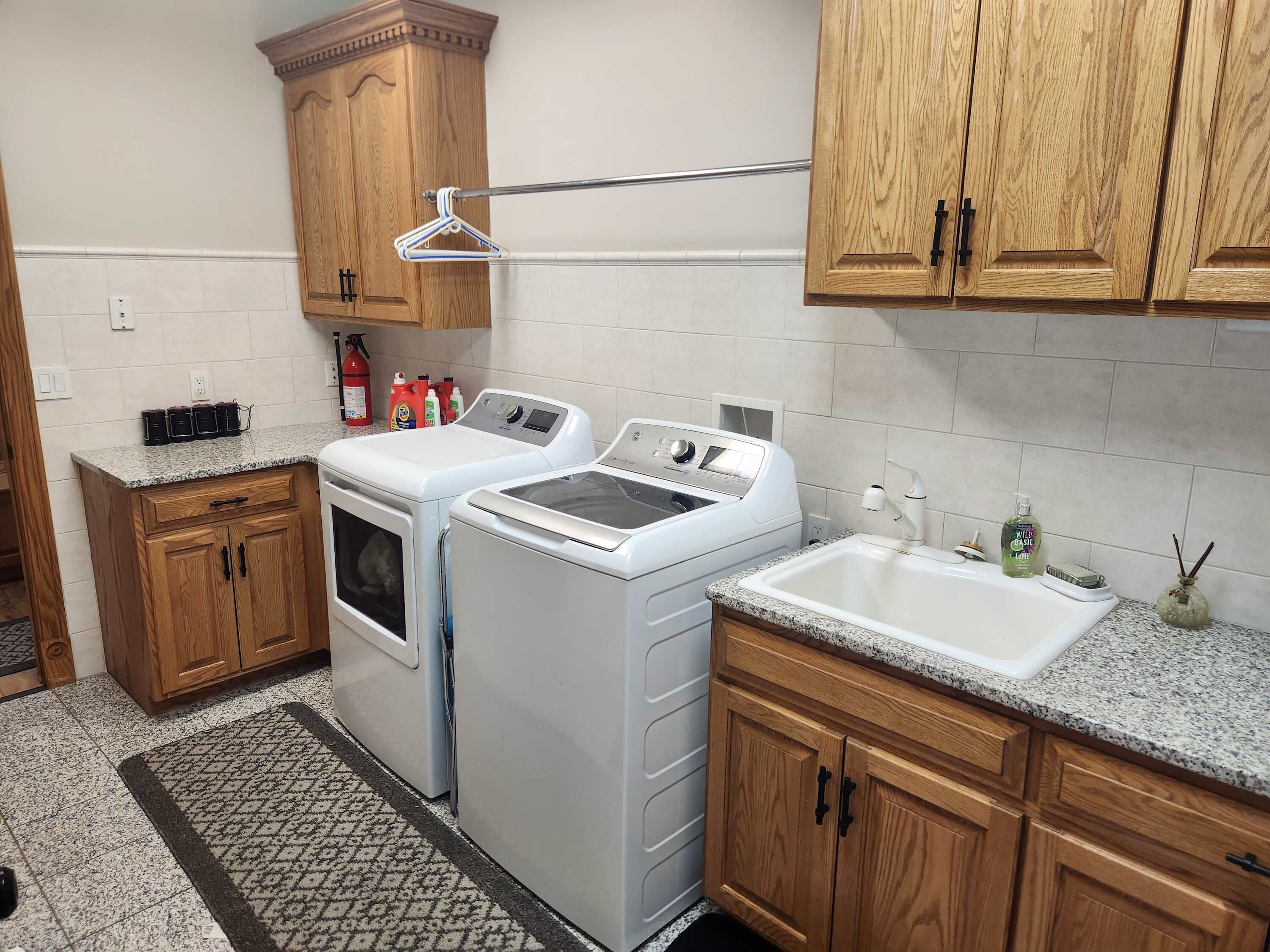 Un área de lavandería con dos lavadoras, un tendedero, armarios de madera y un lavabo.