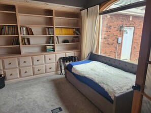 A bedroom with a bed, a bookshelf, and a window.