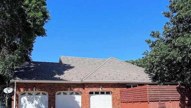 A two-story building with a garage, brick walls, and a sloped roof.