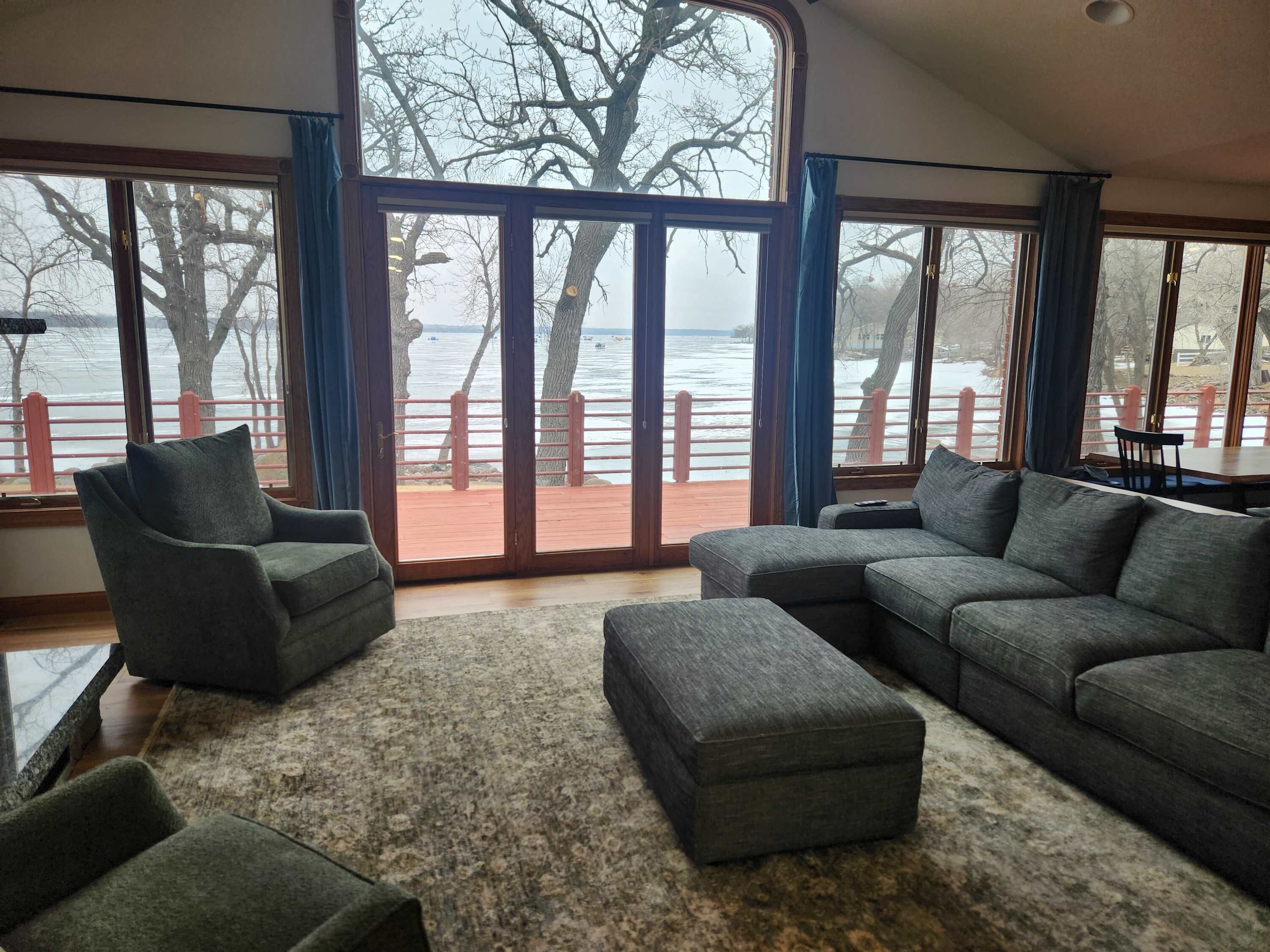 A spacious living room with a large window overlooking a waterfront.