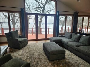 A spacious living room with a large window overlooking a waterfront.