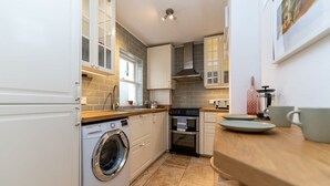 Una cuina compacta amb rentadora, forn i un taulell de fusta.