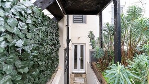 Un carrer estret amb una porta blanca, una reixa de metall i un petit graó que condueix a una porta.