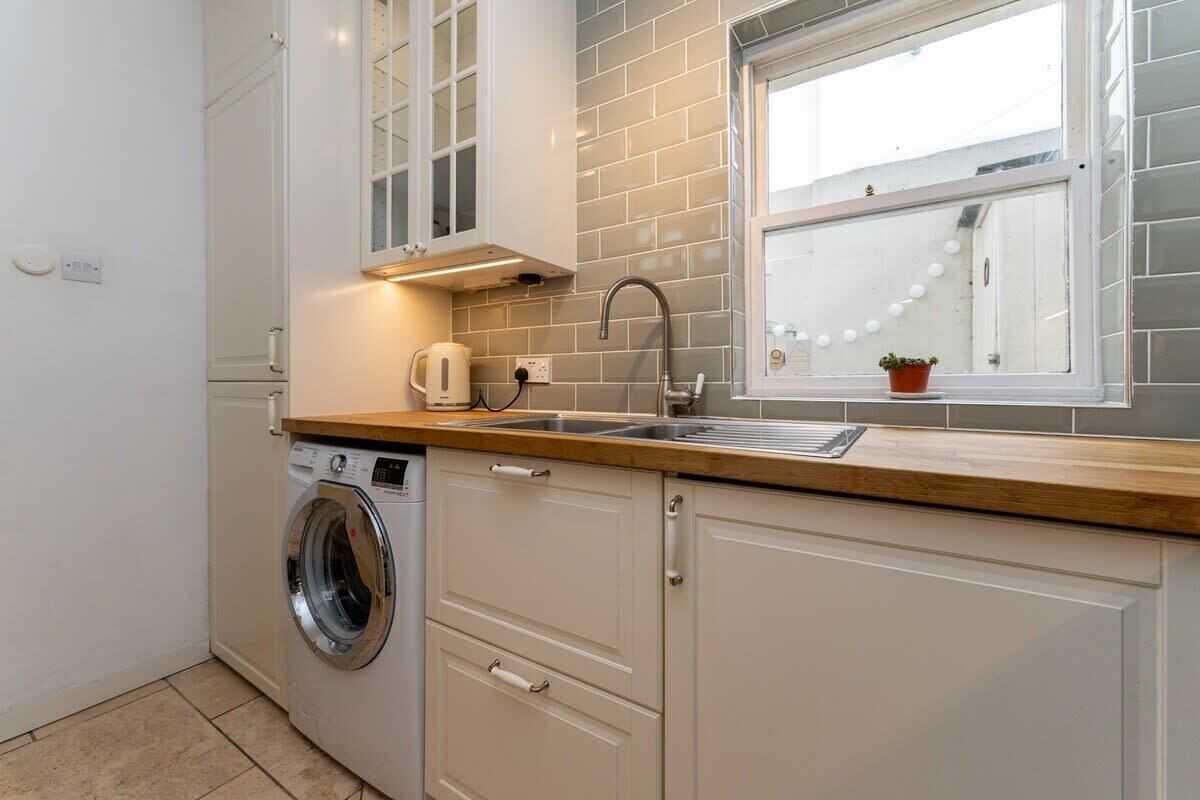 A compact kitchen with a washing machine, a sink, and a window with a view.