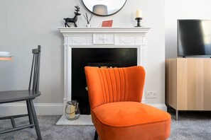 A living room with a fireplace, a television, and a dining area. - Host & Stay | Portland Apartment (Brighton and Hove)
