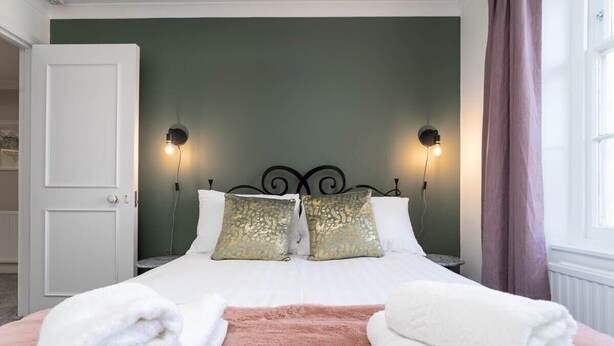 A neatly made bed with two pillows, a pink throw blanket, and two towels on either side. - Host & Stay | Portland Apartment (Brighton and Hove)