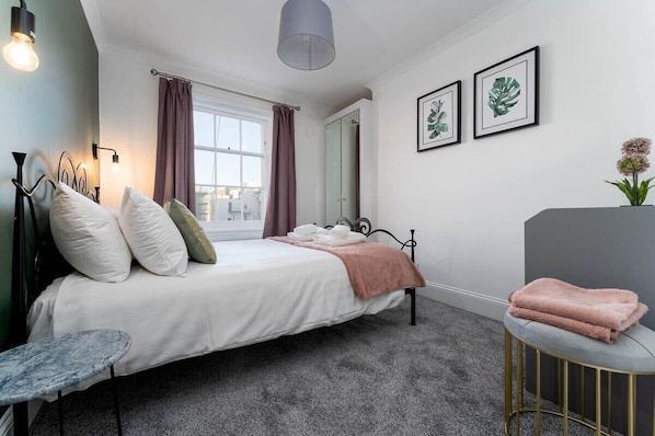 A neatly arranged bedroom with a bed, bedside table, and a small round table.