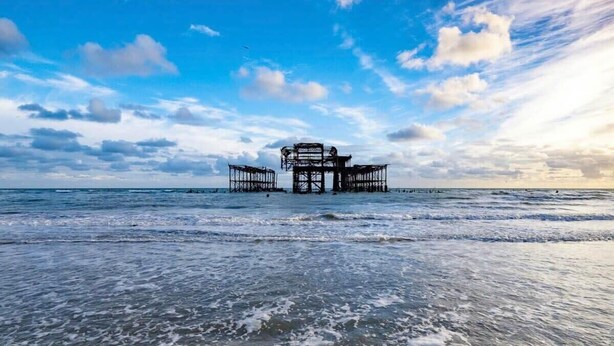 Een kustlandschap met een grote, verlaten pier die zich uitstrekt in de zee.