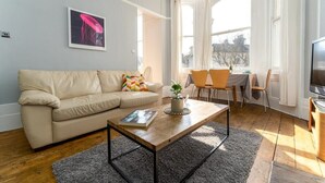 Een moderne woonkamer met een beige bank, een salontafel, en een eethoek met stoelen en een tafel.