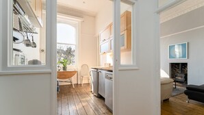 Een moderne keuken met houten vloeren, witte kasten en een eethoek met een houten tafel en stoelen.