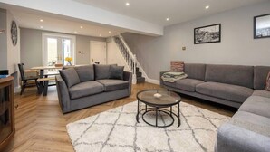 A modern living room with two grey sofas, a coffee table, and a staircase leading to another room. - Host & Stay | Brighton Laines House (Brighton and Hove)