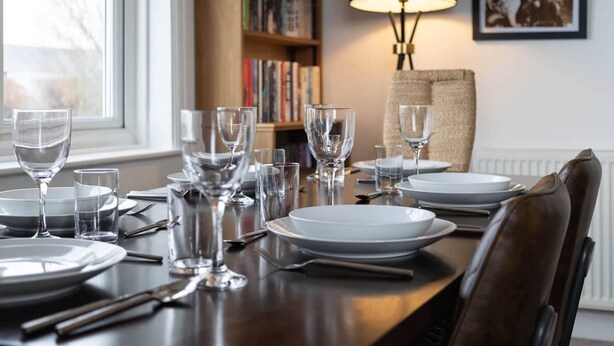 A dining table set with plates, glasses, and cutlery, a lamp, and a bookshelf in the background. - Host & Stay | Preston Park Apartment (Brighton and Hove)