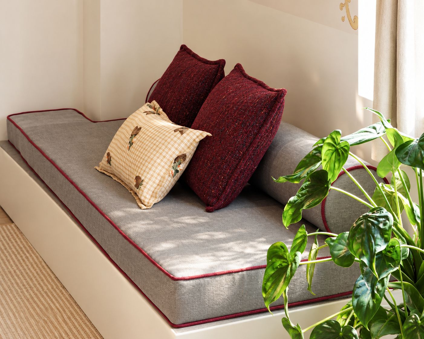 A sofa with a red border, two red cushions, and a checkered pillow with floral patterns.