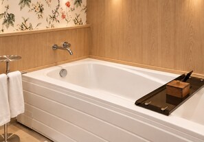 Un baño moderno con una bañera independiente, un tocador de madera y un diseño de papel tapiz floral.