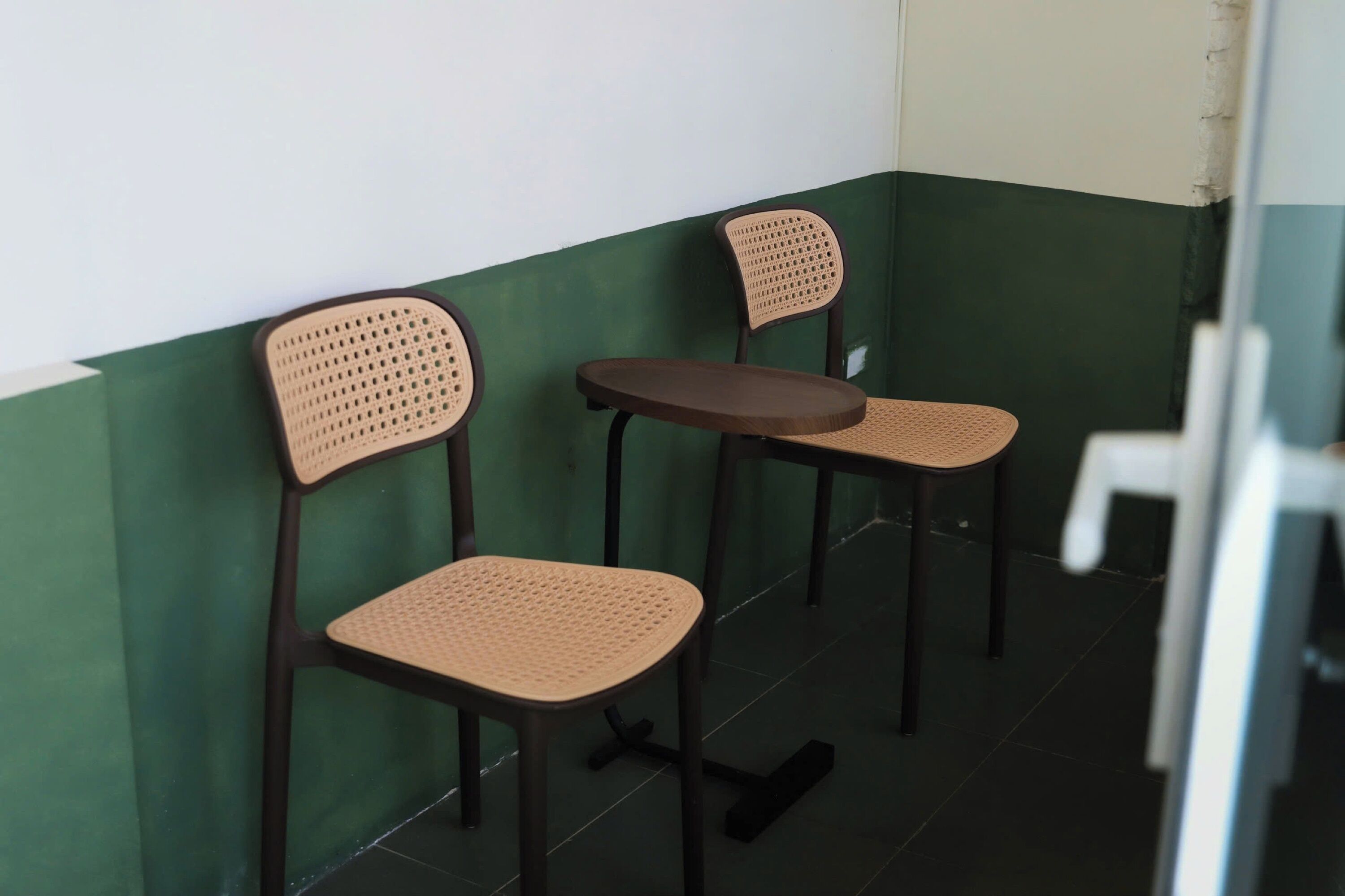 Two chairs and a table in a corner with green and white walls.