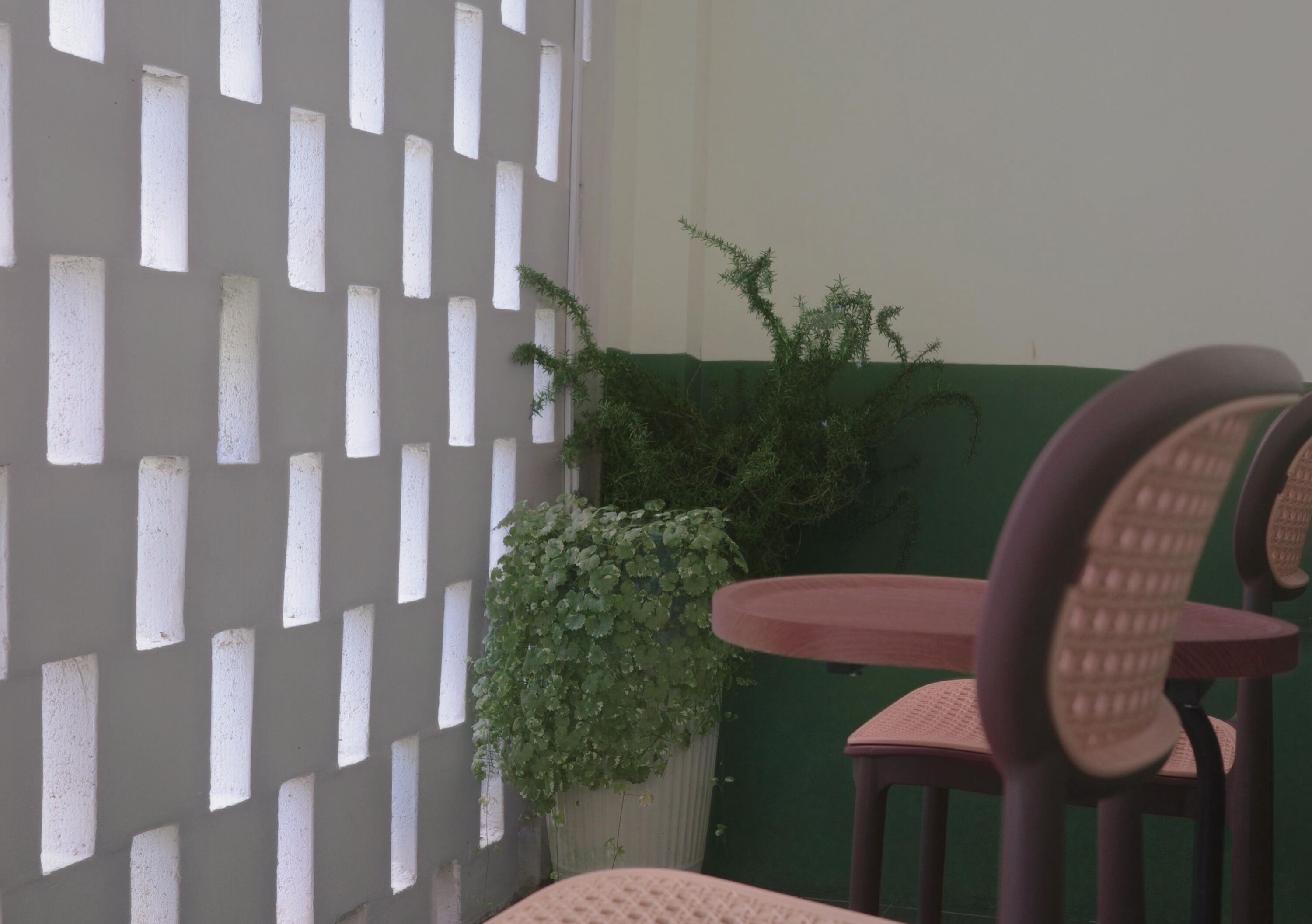Una habitación con un separador blanco, una pared verde y una mesa redonda con sillas.