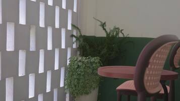 Una habitación con un separador blanco, una pared verde y una mesa redonda con sillas.