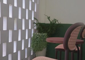 Une pièce avec un mur de séparation blanc, un mur vert et une table ronde entourée de chaises.