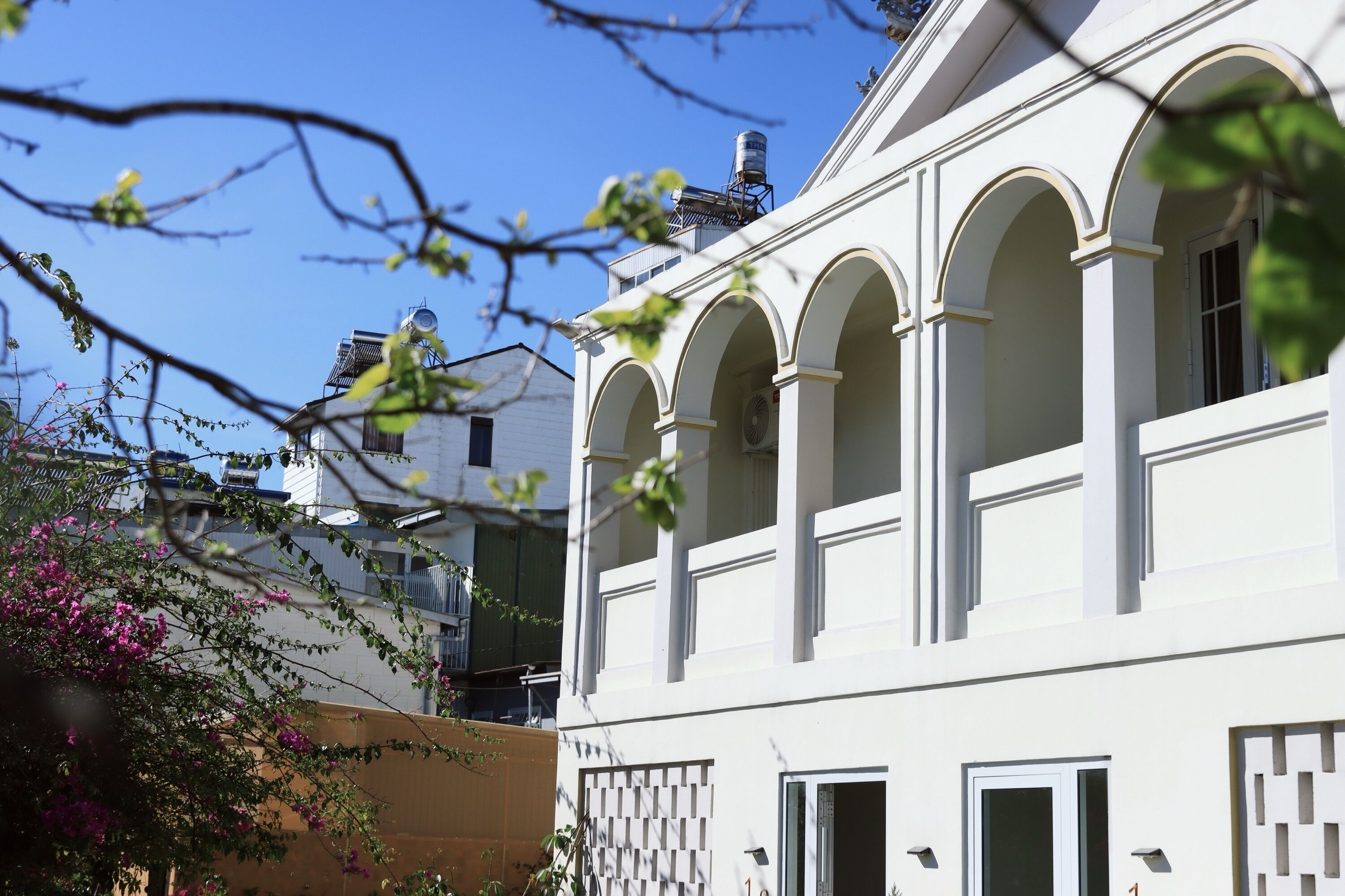 A white building with arched windows and a water tank on the roof.