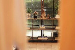 Une pièce avec une table en verre sur laquelle sont exposés des livres, une statue de Bouddha et une figurine de chat.