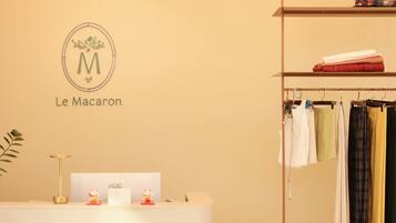 A clothing store interior with a reception desk, a hanging clothes rack, and a wall-mounted sign.