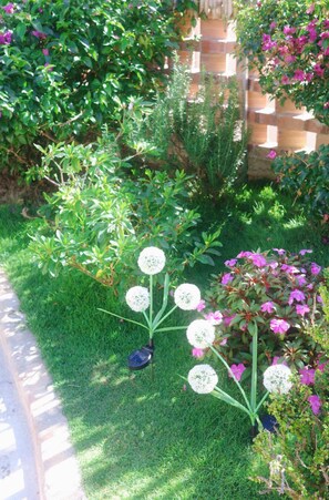 Un jardin où l’on trouve une grande variété de plantes et de fleurs, un mur en briques et une clôture en bois.