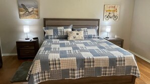 Ein Schlafzimmer mit einem hölzernen Bett, zwei Nachttischen mit Lampen, einer gesteppten Bettdecke und einer Wand mit einem Fahrrad und einem 'LOVE'-Schild.