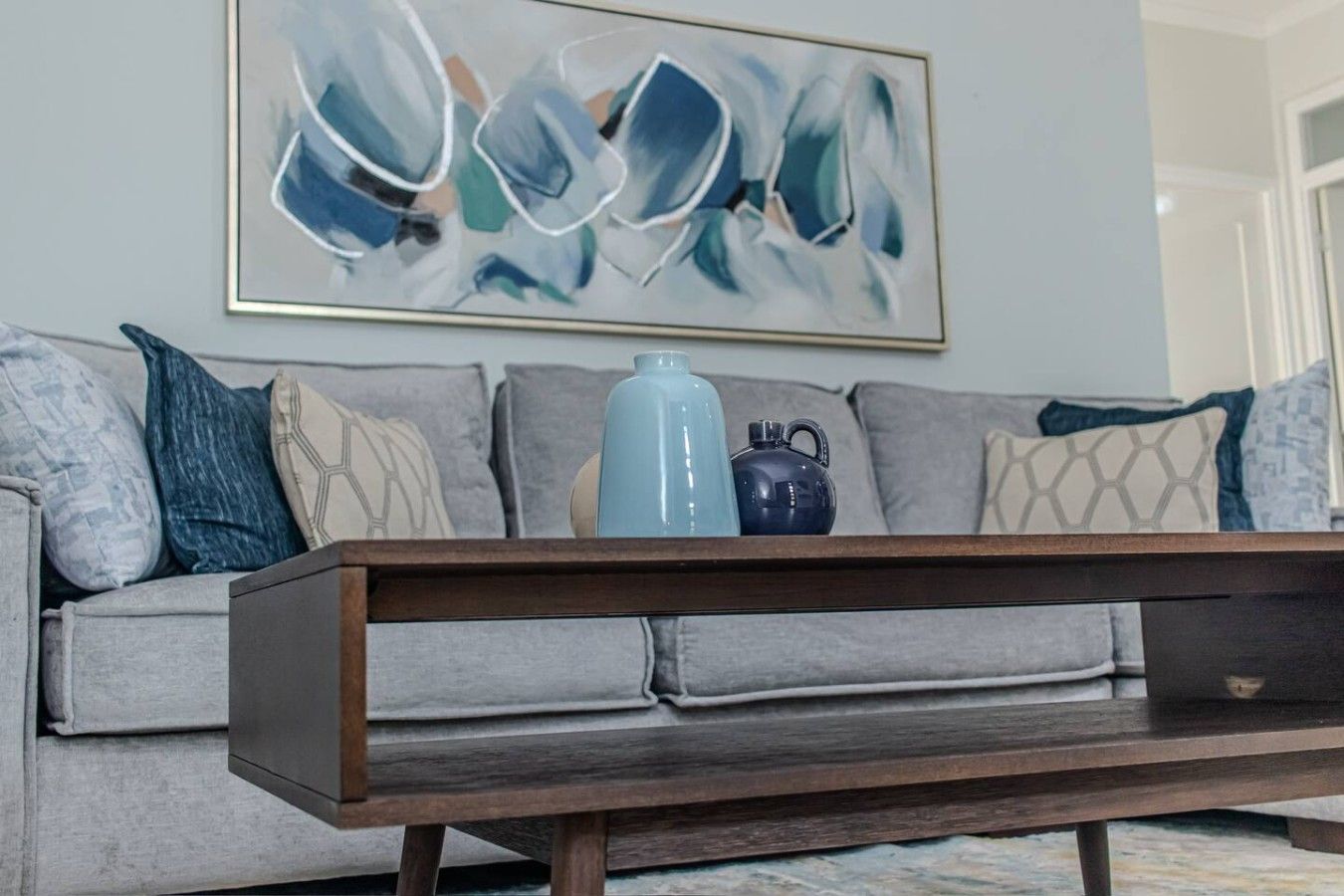 A living room with a grey sofa, a wooden coffee table, and a blue vase.