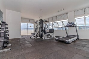A gym with a treadmill, weight bench, and dumbbells.