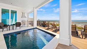 Ein Poolbereich mit Meerblick, Sitzgelegenheiten im Freien und einer überdachten Terrasse.