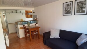 Un espacio habitable compacto con kitchenette, comedor y sofá.