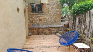Una terraza de madera con dos sillas azules y una pequeña mesa rosa.