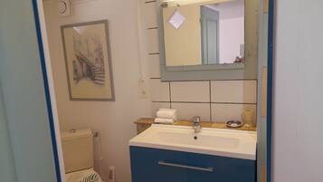 Un bagno con servizi igienici, lavabo, specchio e una cornice con un'immagine appesa al muro.