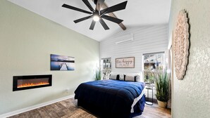 Ein Schlafzimmer mit Bett, Kamin, Deckenventilator und Blick ins Freie.