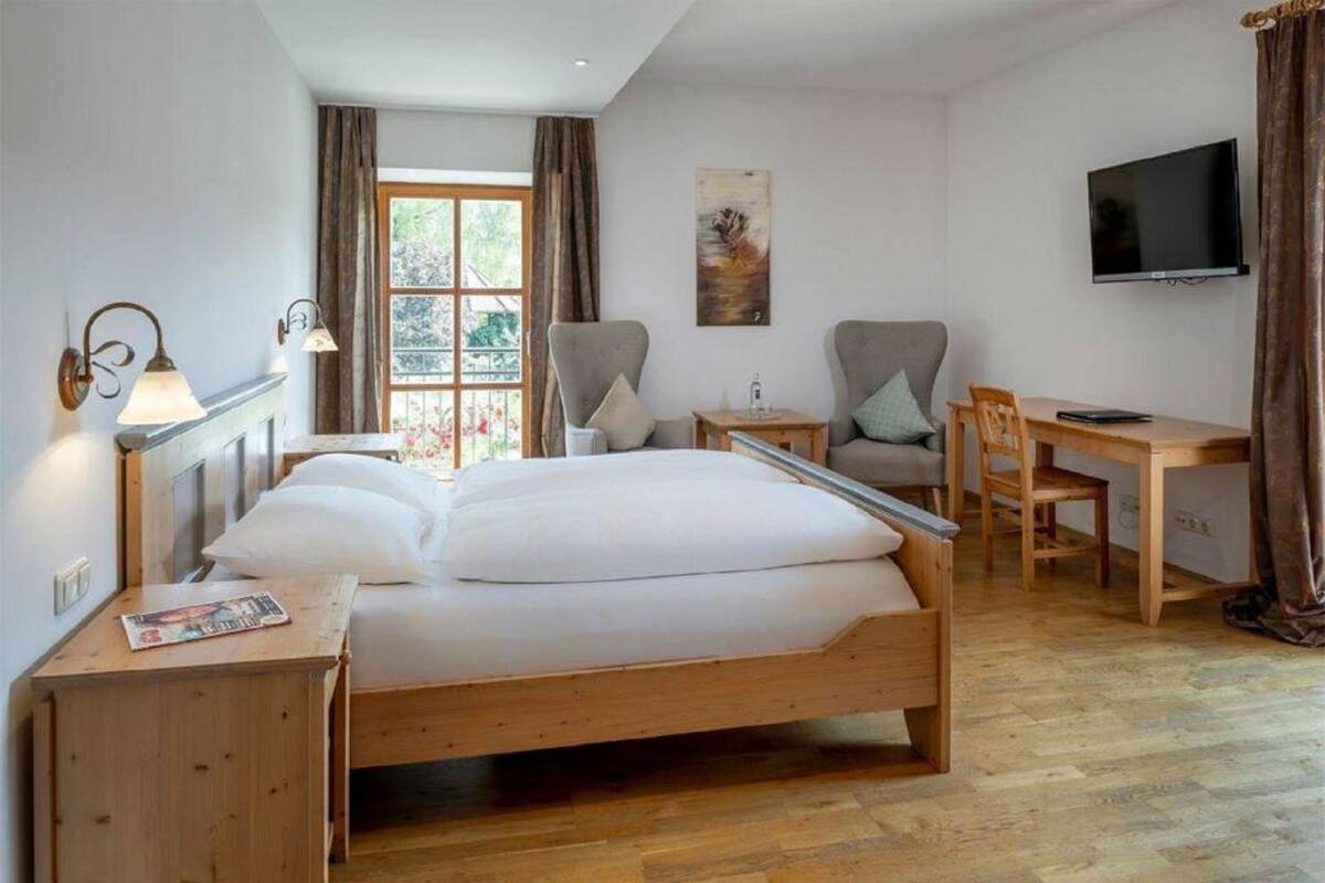 Un dormitorio con cama de madera, escritorio, silla, televisor y ventana con cortinas.