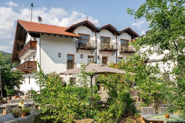 A white building with balconies, outdoor seating, and greenery. - Landgasthof Kammbräu (Zenting)