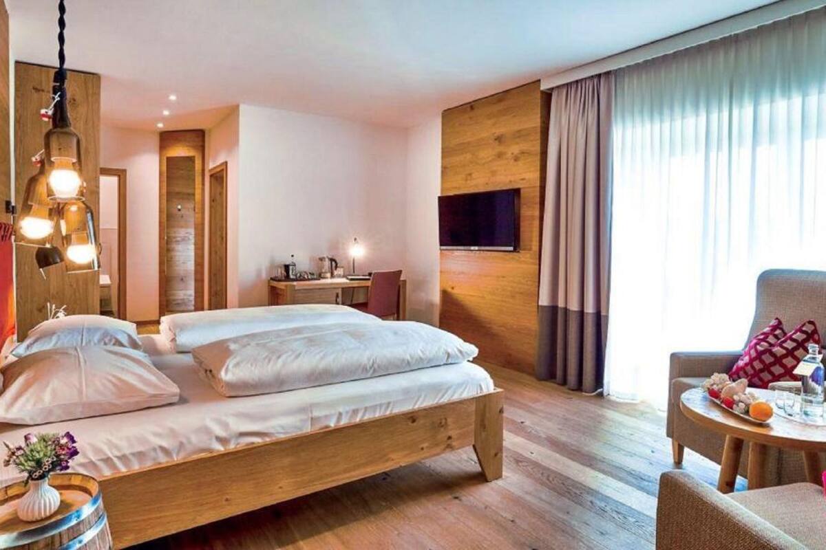 Una habitación de hotel con una cama de madera, un escritorio, una silla y un televisor montado en la pared.