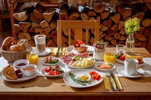A breakfast table with various food items, drinks, and a vase of flowers. - Landgasthof Kammbräu (Zenting)