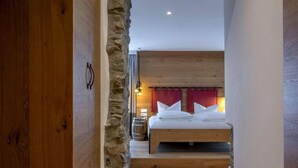 Une chambre avec un lit en bois, un mur en pierre et une tête de lit rouge.