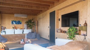 Un espacio de sala cómodo con un sofá, una mesa de centro y un televisor montado en una pared de madera.