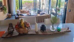 Un comedor con una mesa de madera, una cesta de frutas, velas y un florero con una planta.