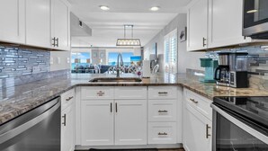 A modern kitchen with white cabinets, stainless steel appliances, and a view to the living area.