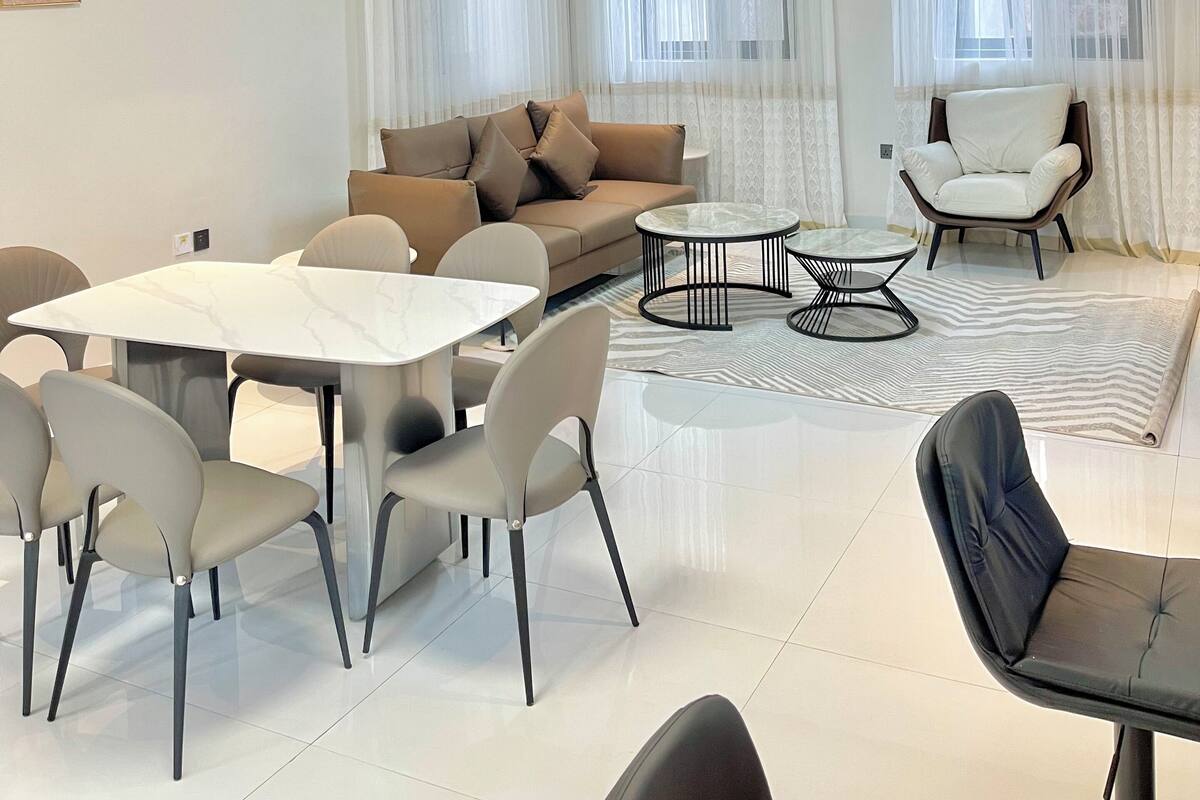 A modern living room with a sofa, dining table, chairs, and a ceiling fan.